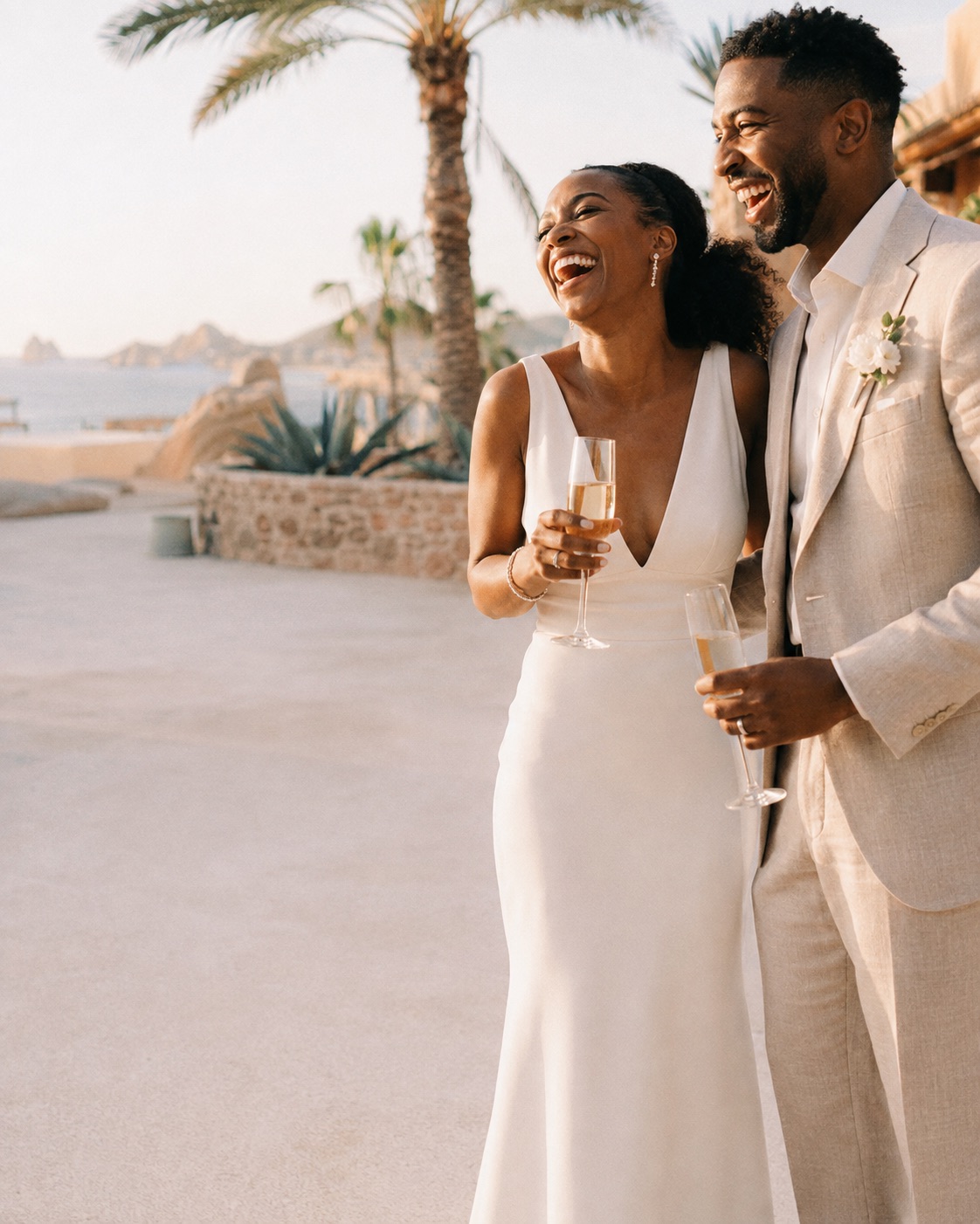 A couple laughing together during their welcome celebration on the coast at golden hour